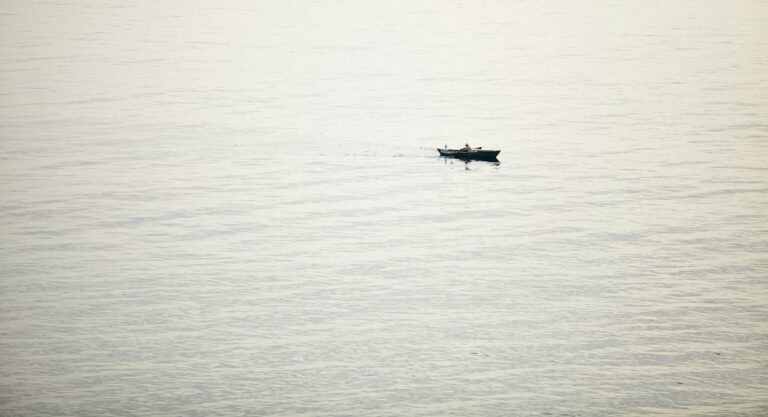 A small boat crossing a calm, pale sea in Mexico.