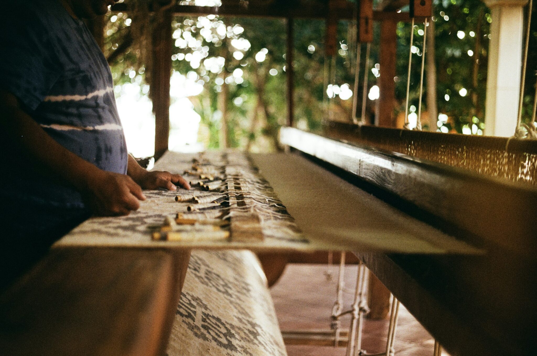 A wooden pedal loom in a weaving workshop in Oaxaca, with a woven textile on the frame.